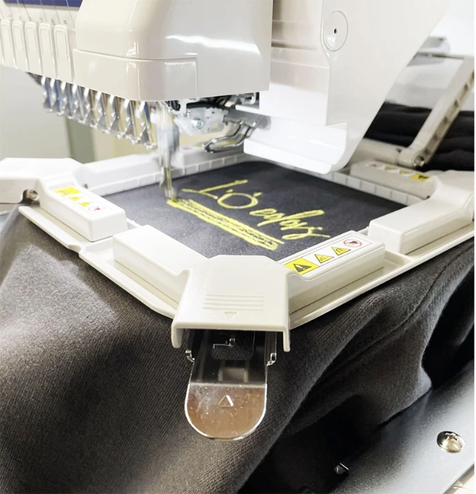 Machine de broderie en train de broder un logo sur textile noir